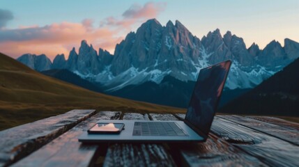Wall Mural - A laptop is open on a wooden table in front of a mountain range