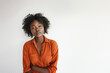 © NaphakStudio - A confident portrait of a young Black woman in a striking orange shirt, her arms crossed and a calm, assertive expression on her face.