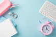 A contemporary flat lay of a stylish workspace featuring school supplies, a pink pencil case, notebooks, and a pastel keyboard on a soft blue background