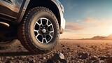 Close-up of a black off-road truck with large all-terrain tires on a gravel road, Pickup car are stopped on a dirt road, from a low-angle view. Gravel road and space for a text