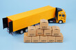 Yellow truck and many shipping carton boxes on blue background. Transportation, delivery and cargo concept.