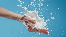 White Lotion Droplets Flying Through The Air With A Reaching Hand. Refreshing And Moisturizing Hand Care.