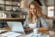 © Ilja - Cheerful woman studying online at home, smiling while using laptop and notebook at desk