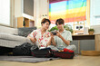 © Prathankarnpap - Homosexual couple packing travel bag for summer vacation in living room