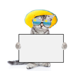 Poster - Tabby kitten wearing sunglasses and summer hat holds blank board. isolated on white background