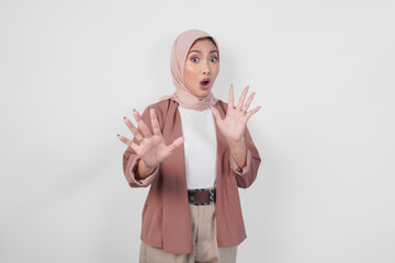 Wall Mural - Displeased Asian woman wearing hijab gesturing a refusal or rejection sign, saying no, asking to stop using hands, standing over isolated white background.