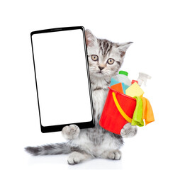 Poster - Cleaning concept. Cute kitten holds bucket with washing fluids and shows  big smartphone with white blank screen in it paw, showing close to camera. Isolated on white background