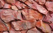 Textured rust red stone wall with a mix of color tones and fragmented pieces.