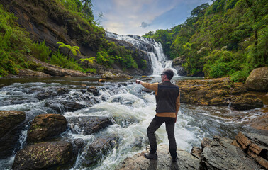 Wall Mural - Hiker observing a waterfall in Sri Lanka