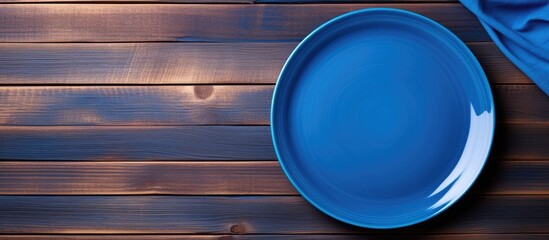 Poster - Empty blue plate and napkin on a wooden background with copy space