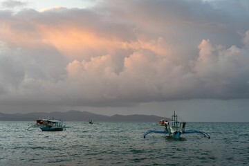 Wall Mural - Boats peacefully sailing in a tranquil ocean setting, with a picturesque sunset in Port Barton