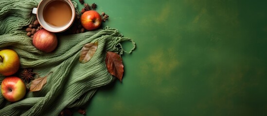Poster - Knitted scarf with warm cup of tea on green background Autumn Fall season Still life Top view Falt lay Copy space