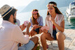 © NDABCREATIVITY - Group of young friends having fun while playing cards on beach at summer vacation