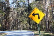 © Wirestock - Yellow road sign of the left turn on a road