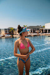 Wall Mural - A trendy and sophisticated woman looks stunning in her blue bikini by the poolside.