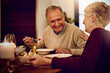 © peopleimages.com - Senior, couple and dinner on date with love on anniversary in retirement with happy marriage. Elderly people, laughing and eating together in fine dining restaurant with food, care and relationship