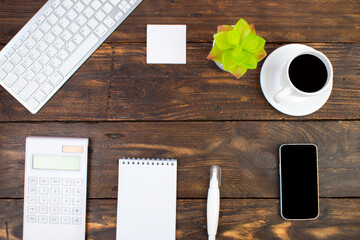 Wooden office table with computer, pen and a cup of coffee, lot of things. Top view with copy space.