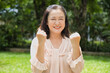 Happy successful asian middle aged asian woman showing yes, good, guts pose for healthy and strong lifestyle in summer green park