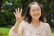 Healthy happy smiling middle aged asian woman pointing 4 fingers up, concept of four points, number four, forth count in summer green park