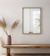 white wall with wooden frame mockup, reflections on the glass of window in the frame, pink vase and dried grass near it, modern style