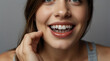 © Prateek - Close up of a young woman holding invisible transparent teeth aligners in hand, braces smile isolated on plain background with copy space