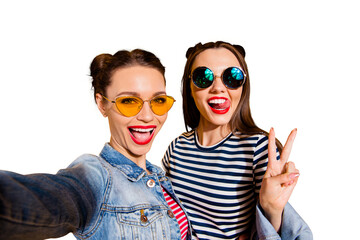 Poster - Glad positive grinning adorable good-looking funky funny two lady isolated on yellow vivid background in casual denim jeans wear trendy glasses spectacles take picture on cellular give v-sign