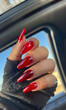 A person holding red acrylic nails in the car.