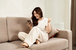 © puhhha - Woman Celebrating Success On Smartphone In Living Room: Happy, Excited, Home Interior, Casual Lifestyle