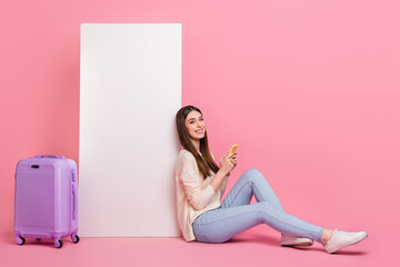 Poster - Portrait of beautiful trendy cheery girl sitting using device booking flight copy space isolated over pink pastel color background