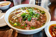 Vietnamese noodle soup with pork in bowl on wooden table