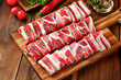 Raw sliced beef on cutting board with herbs and spices on wooden background