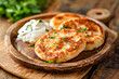 Potato pancakes with sour cream and parsley on a wooden plate