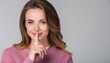 © Marko - Young secret smiling Caucasian woman she wearing casual clothes saying hush be quiet with finger on lips shhh gesture isolated on grey backgroun