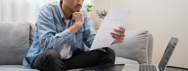 Wall Mural - Household financial economic concept, Stressed Young Asian adults are looking at credit card bills issued documents, and apartment loan mortgages and worrying about having no money to pay.