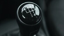Black Image Of A Car Gear Shift. The Gear Shift Is Black And White And Has The Numbers 1 Through 5 On It.