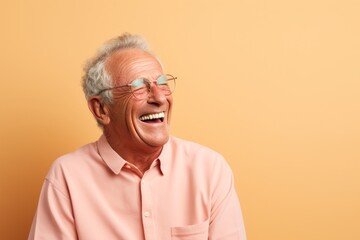 Wall Mural - Portrait of a content man in his 80s laughing over pastel brown background