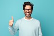 © Markus Schröder - Portrait of a joyful man in his 40s showing a thumb up over soft blue background