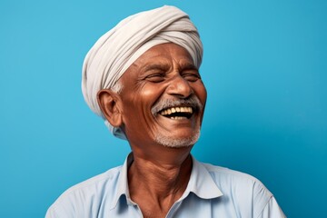 Poster - Portrait of a grinning indian man in his 50s laughing over soft blue background