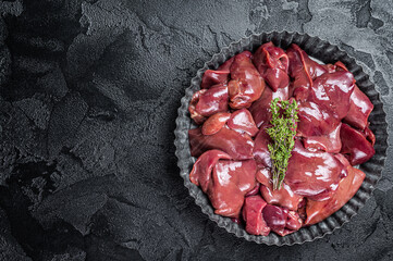 Wall Mural - Uncooked Raw chicken liver, poultry offals in steel plate. Black background. Top view. Copy space