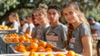 A group of people are standing in front of a pile of oranges
