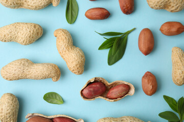 Wall Mural - Fresh peanuts and leaves on light blue table, flat lay