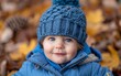 © imagineRbc - A baby wearing a blue hat sits among colorful autumn leaves
