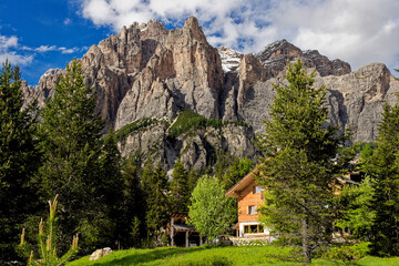 Alpine style house in the Italian Dolomite Mountains. Surrounded by pasture lands and rocky mountains. Alpine Landschaft. Idyllic mountain landscape in the Alps with meadows in summer.