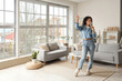 © Pixel-Shot - Young African-American woman with glass of champagne dancing at home