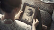 © Generative AI - Memories of childhood nostalgia of youth concept Closeup of caucasian woman looking at her baby vintage photo while sitting on sofa indoors Selective focus on monochrome retro pictures : Generative AI