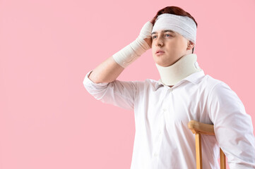 Wall Mural - Injured young man after accident with crutch on pink background