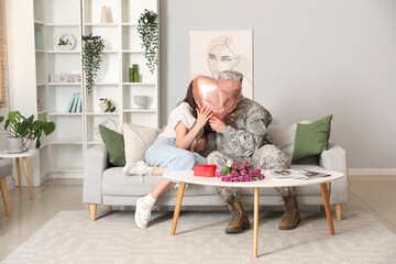 Wall Mural - Man in military uniform and his wife kissing behind heart-shaped balloon at home. Valentine's Day celebration