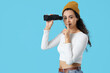 © Pixel-Shot - Young African-American woman with binoculars showing silence gesture on blue background