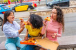 © unai - Friends sharing take away pizza while visiting a city