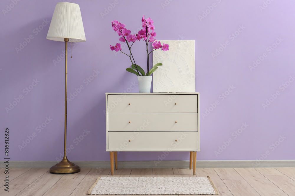 Interior of room with lamp and orchid flower on commode
